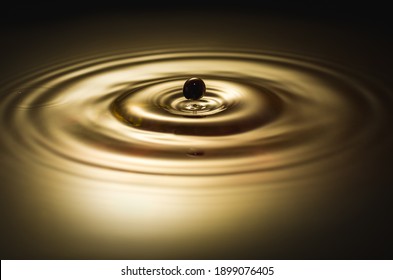 Black Drop Falls Into The Golden Water