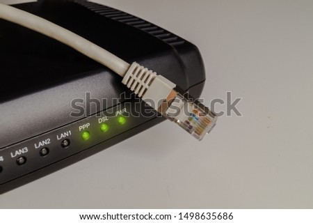 Black dsl modem or router with a network cable on a table. Concept picture for internet, wlan or mobil connections.