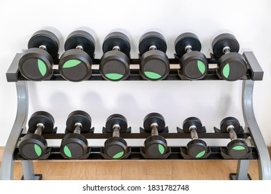Black dumbbell set. Close up many metal dumbbells arrange on rack in sport fitness center.