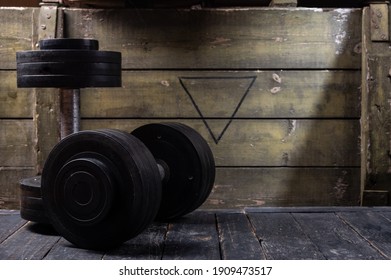 Black dumbbells on the background of a wooden box. Dumbbells and military and green box. - Shutterstock ID 1909473517