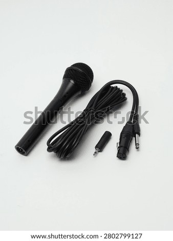 Black dynamic microphone with cable and audio adapter isolated on white background