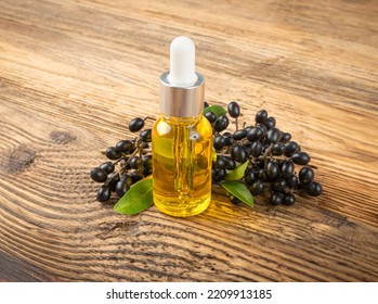 Black Elderberry Oil On Wood Table. Sambucus Berries Essential Oil, Danewort Fruits Extract, Elderberry Extraction, Wild Organic Elder Berry Infusion On Wooden Background