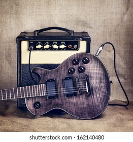 black electric guitar and amplifier on brown canvas background