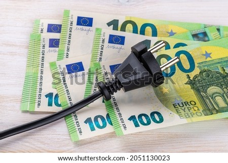 Black electric plug on one hundred euro banknotes. Increasing of electricity cost for residential customers and business users. Payment of electricity bills. Rise in electricity prices concept.