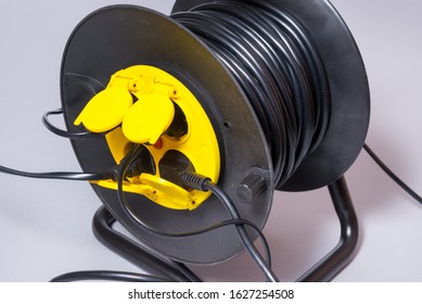Black electrical extension cord on a take-up reel with four sock