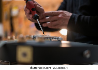 Black electrical guitar in repair service shop with a hands of a guitar luthier which fixes and tightens it