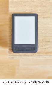 black electronic book with empty screen on wooden table and free space for advertise text top view. Vertical shot.