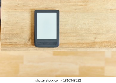 black electronic book with empty screen on wooden table and free space for advertise text top view. Horizontal shot.