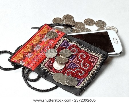 Black embroidered fabric bag for your white phone and coins placed on a white background. Close -up shot of the bag.