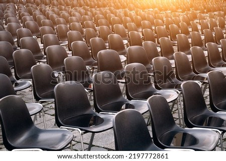 A lot of black empty plastic chairs stand on the street
