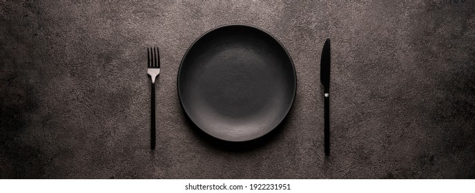 black empty plate and cutlery, fork and knife, on a dark textured background. Mockup concept for the design of a restaurant menu, website or design. long panoramic layout, central composition - Shutterstock ID 1922231951