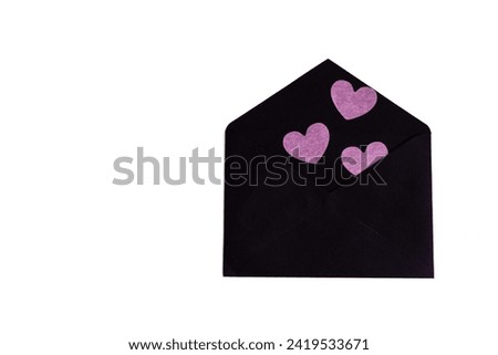 black envelope with black and pink paper hearts on a light background. preparation for Valentine's Day. a gift for Valentine's Day. an invitation to love. copy space 