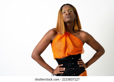 Black Ethnic Man In A Studio, LGTBI Concept, Wearing An Orange And Black Dress And Wearing A Wig