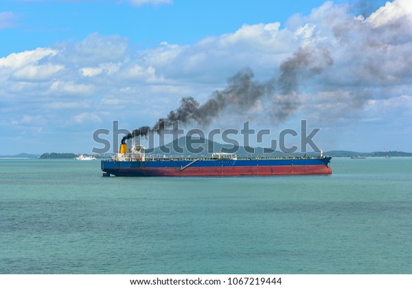 Black exhaust fumes coming from the\
chimney of an moored tanker after main engine\
ignition.
