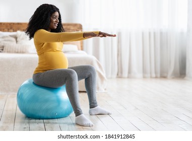 Black Expecting Woman Training On Ball, Getting Ready For Childbirth. Smiling African Pregnant Lady With Big Tummy Sitting On Fitness Ball In Bedroom, Looking At Copy Space. Sport During Pregnancy