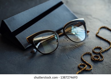 Black eyeglasses with transparent lenses and black case on dark concrete background. Close up view