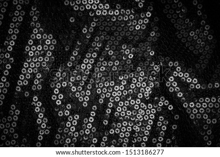 Black fabric background, copy space. Metal glitter black cloth background, close up. Trendy Metallic dark fabric texture. Black sequins, glow sequined textile