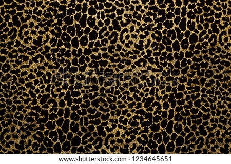 Black fabric with metallic golden leopard fur print. Retro fashion background.