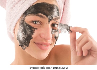 Black facial mask. beautiful girl piling off black mask. beauty concept