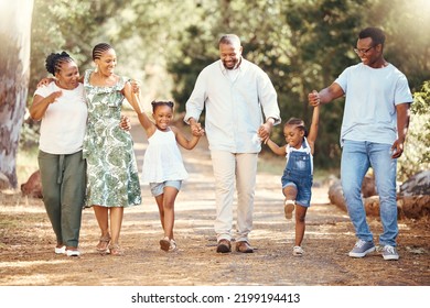 Black Family, Hiking Or Bond With Children, Parents Or Grandparents Walking In Remote Nature Forest And Countryside. Happy Mother, Father Or Senior Holding Hands With Girls And Skipping In Tree Park