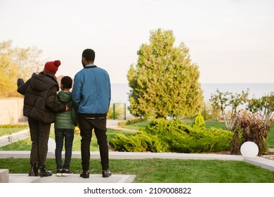 Black Family Hugging While Standing On Yard Outdoors