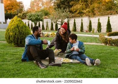 Black family laughing during picnic on blanket at backyard outdoors - Powered by Shutterstock