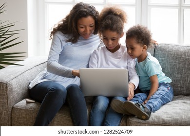 Black Family Mom With 2 Kids Using Laptop Together At Home, African American Mother Teaching Children Learning Computer Apps Use, Explaining Online Education To Focused Little Son And Daughter