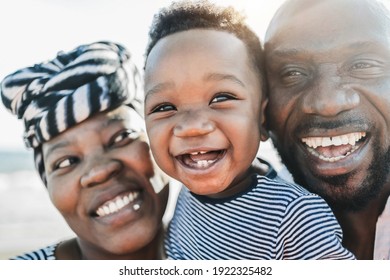 Black Family On The Beach - Mother, Father And Little Son Looking In Camera And Smiling -  Main Focus On Kid Eye