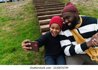 Black Family Taking Selfie On Cellphone And Laughing While Resting Outside City