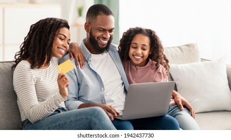 Black Family Using Computer And Credit Card At Home