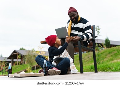 Black Family Using Gadgets And Eating Pizza While Resting Outside City