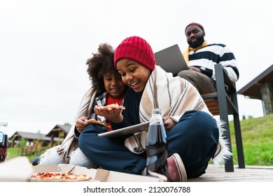 Black Family Using Gadgets And Eating Pizza While Resting Outside City