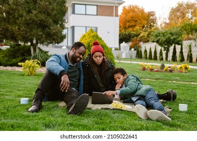 Black Family Using Tablet Computer During Picnic At Backyard Outdoors