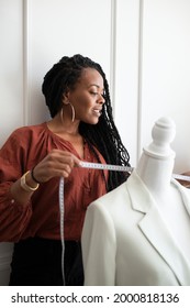 Black Fashion Designer Measuring A White Coat On A Pinnable Mannequin