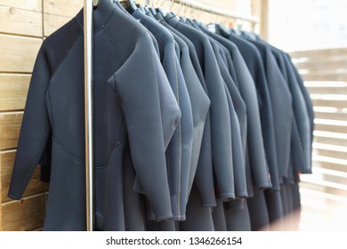 Black fashionable   surfing wetsuits hanging on rack for rent in surf club - Powered by Shutterstock