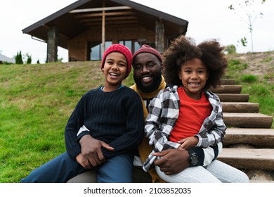 Black Father Laughing While Making Fun With His Sons While Resting Outside City