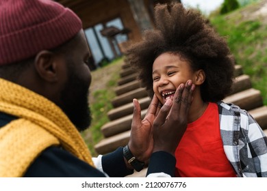 Black Father Laughing While Making Fun With His Son While Resting Outside City