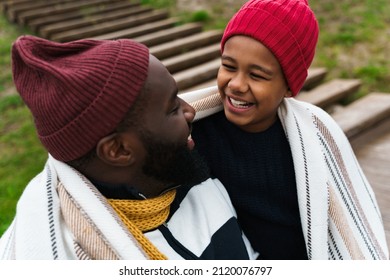 Black Father Laughing While Making Fun With His Son While Resting Outside City