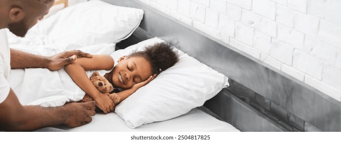 Black father lovingly tucks in his child who is snuggled under a warm blanket, holding a teddy bear. The child smiles contentedly, surrounded by soft pillows in a serene bedroom atmosphere. - Powered by Shutterstock