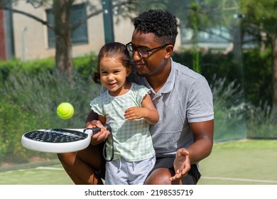 Black father teaching daughter to play paddle tennis  - Powered by Shutterstock