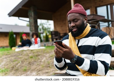 Black Father Using Cellphone While Resting With His Sons Outside City