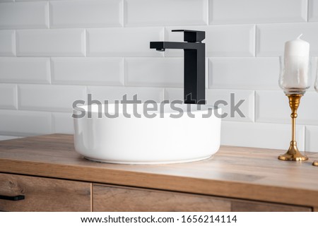 Black faucet for water and white separate high sink on wooden pedestal. Loft style bathroom.