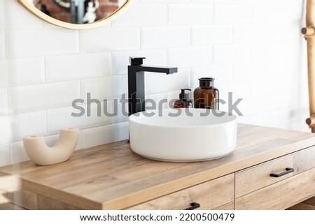 Black faucet for water and white separate high sink on wooden pedestal. Loft style bathroom.