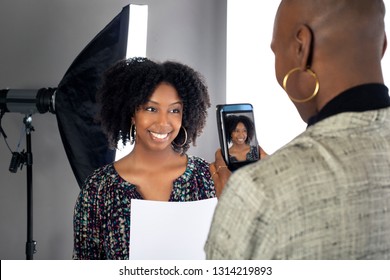 Black Female Actress Doing A Self Tape Audition Via Cell Phone Camera In A Studio While Reading To A Casting Director.  Depicts The Hollywood Entertainment Industry Process.