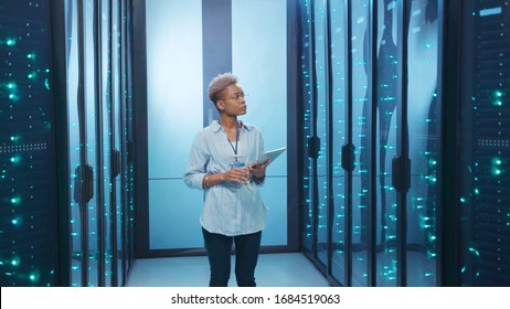 Black Female Administrator With Tablet Activating Network Servers In Database Digital Room. Satisfied Woman Professional Is Happy Of Successful Work Operation Working In Data Center.