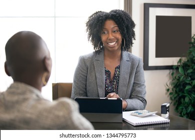 Black female businesswoman in an office with a client giving legal advice about taxes or financial loans. The woman could be a lawyer or a cpa accountant.