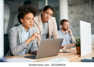 Black Female CEO Using Laptop While Working With Colleagues In The Office.