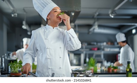 Black Female Chef Takes Fresh Herb, Smells It with a Smile, Secret Ingredient that Makes Grandmother's Recipe Special. Traditional Restaurant Kitchen with Authentic Dish, Healthy, Nurturing Food - Powered by Shutterstock