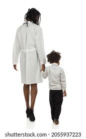 Black Female Doctor And Small Boy Are Walking Together Holding Hands. Rear View. Full Length Studio Shot Isolated.