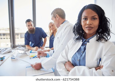 Black Female Doctor Standing With Arms Crossed And Looking At Camera During The Meeting In Hospital.